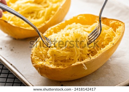 Spaghetti squash baked and pulled apart with two forks, ready to eat on a baking pan