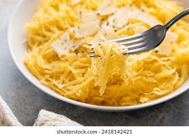 Spaghetti squash roasted and pulled apart served with olive oil and parmesan, low carb recipe idea, with a fork swirled in