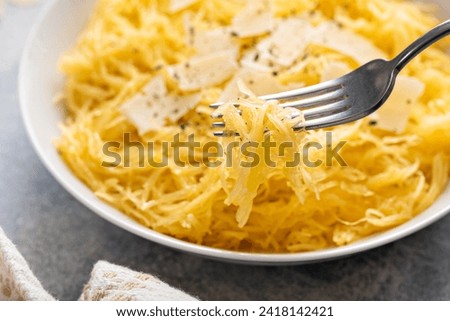 Spaghetti squash roasted and pulled apart served with olive oil and parmesan, low carb recipe idea, with a fork swirled in