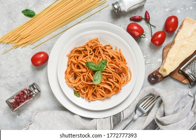 Spaghetti with tomato sauce with basil on a grey background