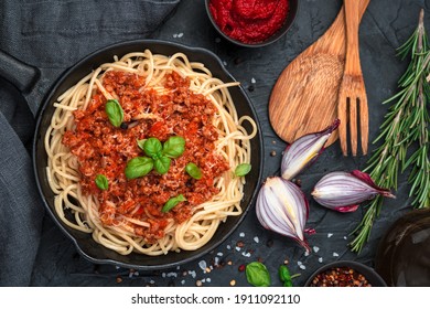 Spaghetti and tomato sauce with minced meat and fresh basil on a black background. Top view, horizontal. The concept of culinary backgrounds.