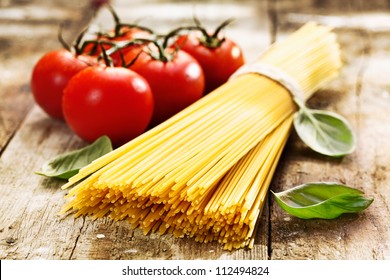 Spaghetti And Tomatoes With Herbs On An Old And Vintage Wooden Table