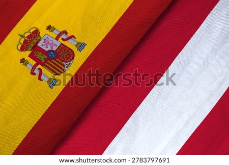 Spain and Austria flags overlapping, close-up fabric texture, symbolizing diplomacy, sportsmanship, and European international competition.