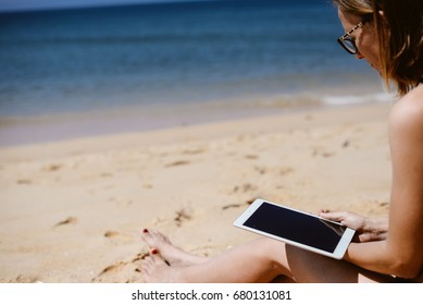 Spain, Europe - 24 June 2017: Busy Woman Using Apple Ipad 2 Smart Computer Device On Sandy Sea Beach Outdoors Background. Back Side View Of Modern Internet Working Person And Blank Display Copyspace