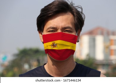Spain flag on hygienic mask. Masked Asian man prevent germs. concept of Tiny Particle protection or virus corona or Covid19. - Shutterstock ID 1671446134