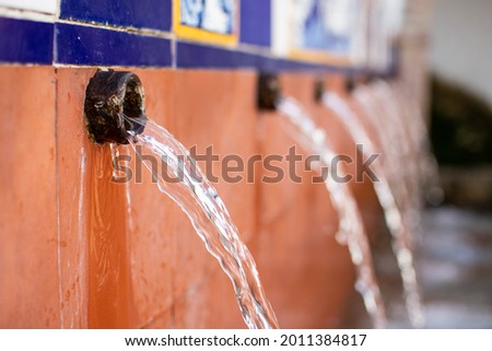 ISTÁN, SPAIN: Flowing spring water at Fuente y Lavadero El Chorro, a tiled public fountain, historically used by residents for drinking water and washing clothes before the houses had flowing water