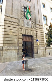 Córdoba, Spain - Jul 12, 2011: 
A Young Girl Drinking Water In A Fountain In Front Of The Postal Office And Telegraph Building (Correos Y Telegrafos) Of Córdoba, Andalusia, Spain