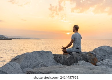 Spain. man meditating during sunrise on rocky beach - Powered by Shutterstock