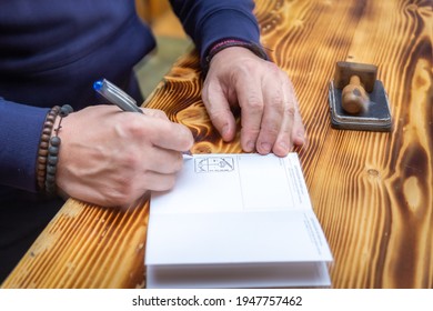 FONCEBADÓN, SPAIN - MARCH 6 2020: Hostel Tenant Putting Stamp In Pilgrim Pasport Credencial On The Way Of St James Pilgrimage Trail Camino De Santiago