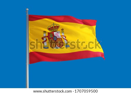 Spain national flag waving in the wind on a deep blue sky. High quality fabric. International relations concept.