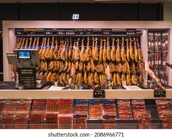 Málaga, Spain: November-26-2021. Iberian Hams Hang On The Wall Of A Supermarket Ready For Christmas. There Are Several Types Of Ham: Iberian Acorn, Black Leg, Field Bait And Iberian Bait