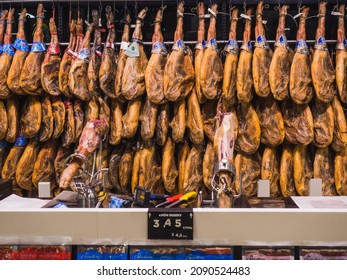 Málaga, Spain: November-26-2021. Iberian Hams Hang On The Wall Of A Supermarket Ready For Christmas. There Are Several Types Of Ham: Iberian Acorn, Black Leg, Field Bait And Iberian Bait