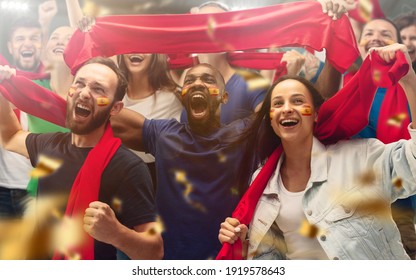 Spainian football, soccer fans cheering their team with a red scarfs at stadium. Excited fans cheering a goal, supporting favourite players. Concept of sport, human emotions, entertainment. - Powered by Shutterstock