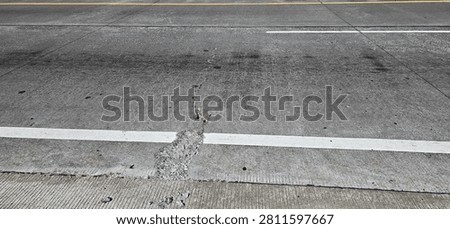 Spalling damage to the rigid pavement at the center of the toll road slab.