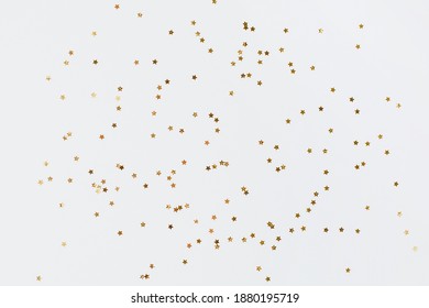 Spangles of gold and silver are scattered from bottles on a white background