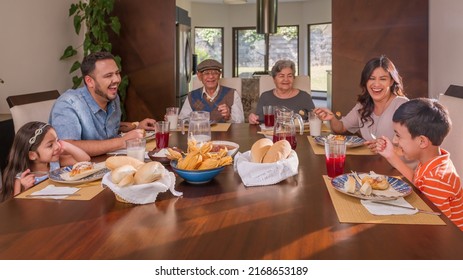 Spanic family. Parents grandparents, and grandchildren sitting at the dining room table sharing a meal. - Powered by Shutterstock