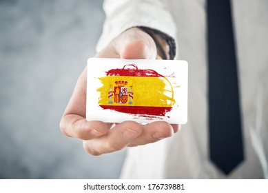 Spanish Businessman Holding Business Card With Spain Flag. International Cooperation, Investments, Business Opportunities Concept.