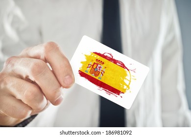 Spanish Businessman Holding Business Card With Spain Flag. International Cooperation, Investments, Business Opportunities Concept.