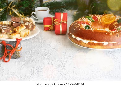 Spanish Christmas concept , Roscon de reyes  or Spanish holiday cake with hot chocolate, sweet coal  and turrones candies, red Christmas gifts on white background .Copy space