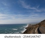 Spanish coastline in Andalusia on a sunny but windy day. Coastal road along a long sandy beach. one can see many big waves on the ocean die to the wind. Travel, adventure, exploration and free mindset