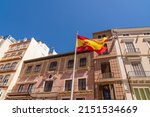 Spanish flag in the old town of the city of Malaga. Beautiful typically Spanish buildings architecture in background. Blue sky in a sunny summer day