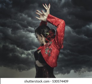 Spanish Flamenco Dancer With Bun In Hair And Red Coat With Storm Background In The Sky