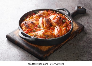 Spanish food chicken baked with tomato, pepper, onion and garlic sauce close-up in a frying pan on a cutting board. horizontal