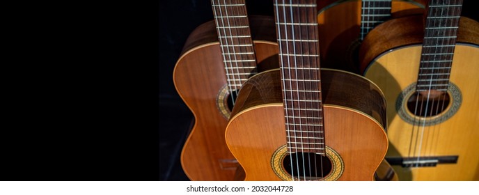 Spanish guitars for an instrumental concert concept. Perfect musical instruments on a black background. Guitar heads, necks, and silver and nylon strings. Ensemble performance, party. - Shutterstock ID 2032044728