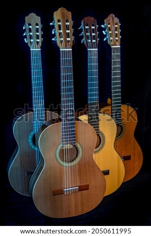 Spanish guitars for an instrumental concert concept. Perfect musical instruments on a black background. Guitar heads, necks, and silver and nylon strings. Ensemble performance, party.