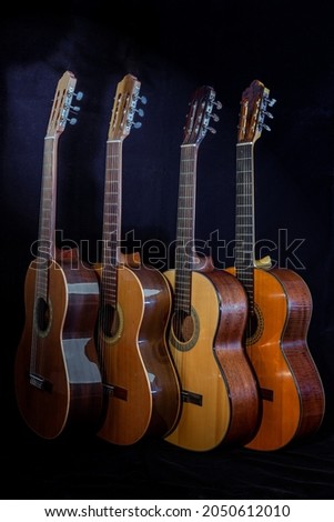 Spanish guitars for an instrumental concert concept. Perfect musical instruments on a black background. Guitar heads, necks, and silver and nylon strings. Ensemble performance, party.