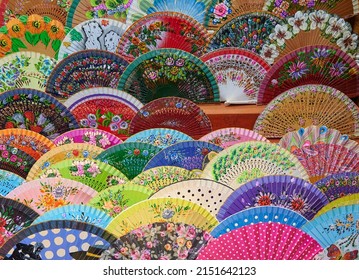 Spanish Hand Fans Made By Local Artisan, Painted By Hand Are On Sale In A Bazaar Like Souvenirs. Hand Craft Items.