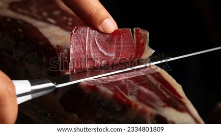 Spanish Iberian ham. Iberian ham slicer with knife that makes the best slice for tasting. Spanish Iberian ham slicer with knife with selective focus and black background for copy space.