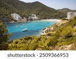 The Spanish island of Ibiza showing the beautiful beach front on and the beach at Cala Llonga in the summer time in the Balearic Islands, Spain