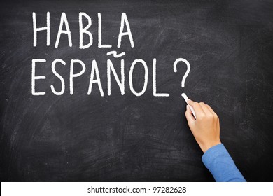 Imagen conceptual del aprendizaje en español. Profesora o estudiante que escribe "habla espanol" en la pizarra durante la clase de español.