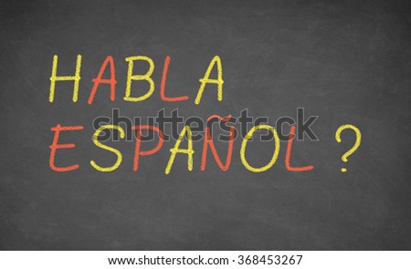 Spanish language learning concept image. Teacher or student wrote HABLA ESPANOL on blackboard during spanish language course class.