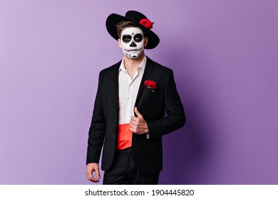 Spanish Man With Face Art On Halloween Posing In Black Suit On Purple Background