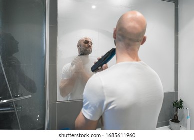 A Spanish Man Shaves His Beard With A Wireless Grooming Trimmer In Front Of A Steamy Mirror In The Bathroom Of A House In Edinburgh, Scotland, United Kingdom