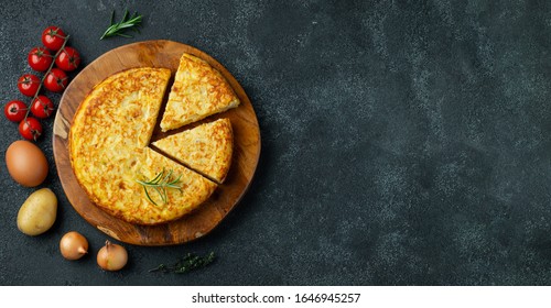 Spanish omelette with potatoes and onion, typical Spanish cuisine on a black concrete background. Tortilla espanola. Top view with copy space