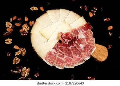 Spanish serrano ham platter with Manchego cheese and nuts on a black background - Shutterstock ID 2187220643