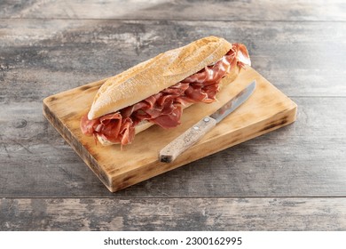 Spanish serrano ham sandwich on wooden table - Shutterstock ID 2300162995