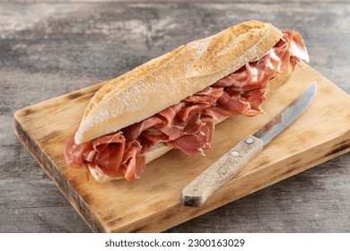 Spanish serrano ham sandwich on wooden table - Shutterstock ID 2300163029