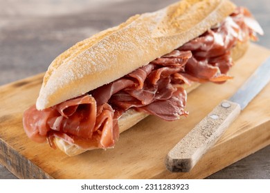 Spanish serrano ham sandwich on wooden table - Shutterstock ID 2311283923