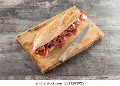 Spanish serrano ham sandwich on wooden table - Shutterstock ID 2311283925