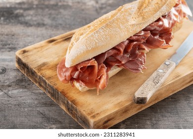 Spanish serrano ham sandwich on wooden table - Shutterstock ID 2311283941