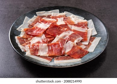 Spanish serrano ham slices on black plate on black slate background - Shutterstock ID 2088214990