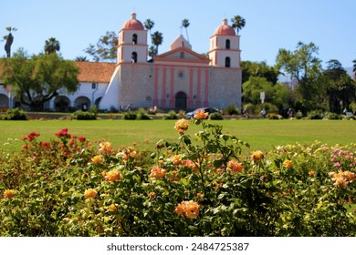 Spanish style historical mission surrounded by a Rose Garden and a manicured lawn taken in the Santa Barbara, CA Mission where people can relax at a park and tour the historic mission - Powered by Shutterstock