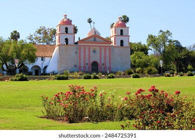 Spanish style historical mission surrounded by a Rose Garden and a manicured lawn taken in the Santa Barbara, CA Mission where people can relax at a park and tour the historic mission - Powered by Shutterstock