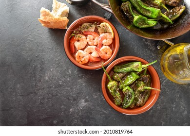 Spanish Tapa Bowls With Fried Pimientos Or Padron Peppers And Shrimps With Lemon And Herbs On A Gray Slate Background, Copy Space, High Angle View From Above