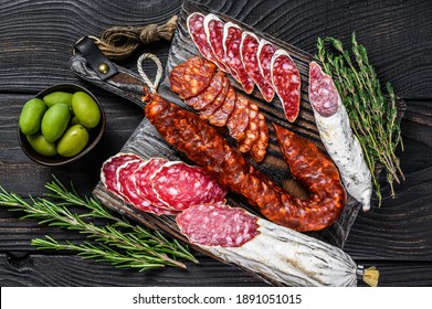 Spanish tapas sliced sausages salami, fuet and chorizo on a wooden cutting board. Black wooden background. Top view.