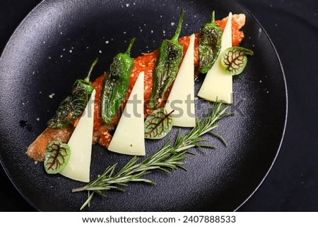 Spanish traditional appetizer Pan con Tomate with Manchego cheese and Pimientos de Padron peppers